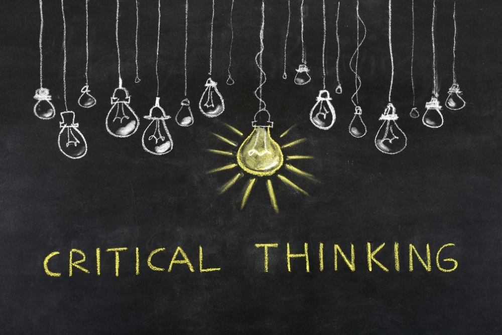 Several unlit light bulbs and one lit light bulb with the word Critical thinking in the foreground
