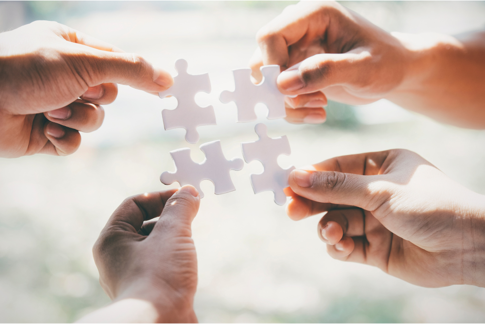 Four People Connecting Four Pieces of Puzzle