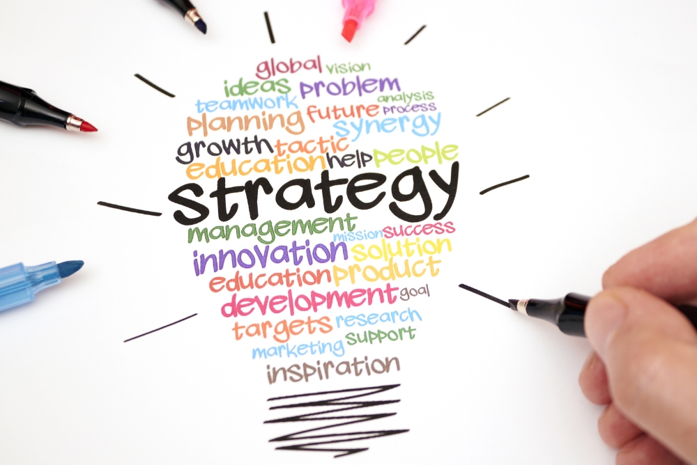 Words in the shape of a bulb related to strategy and planning and a pen tip