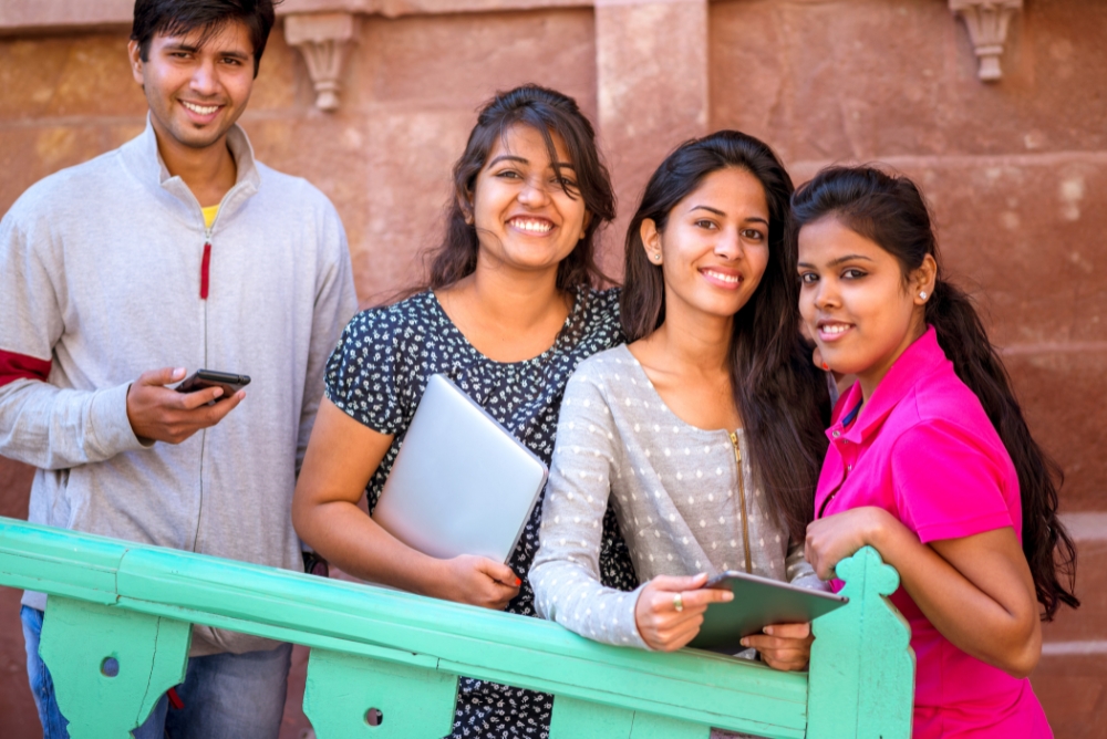 People smiling and standing with technological devices in their hand on a stair case